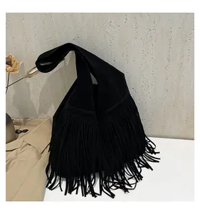 Detail of black suede tote bag with long bohemian fringes and wide shoulder strap