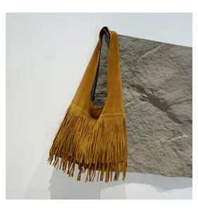 Close-up of tan brown suede tote bag with long fringe tassels and wide shoulder strap
