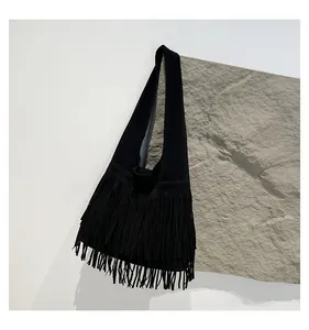 Detailed close-up of a black fringe suede tote bag with long bohemian tassels and shoulder strap