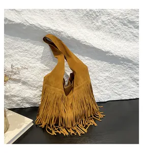 Detailed close-up of ginger yellow suede tote bag featuring long bohemian tassels