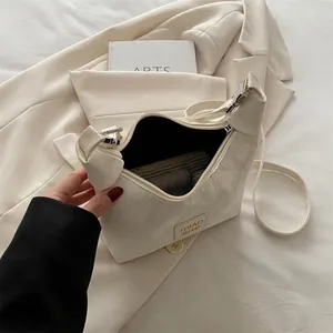 Cream shoulder bag with MIAO SHE label and zipper, styled with a blazer and book