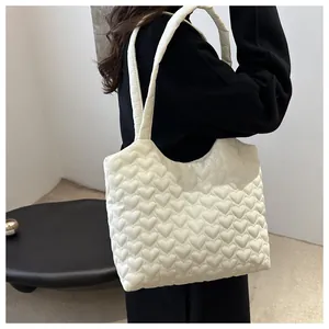 Femme portant un sac cabas blanc matelassé avec motifs de cœur pour tenue décontractée