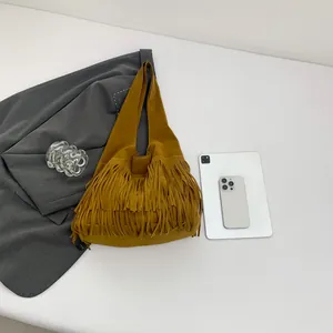 Flat lay of a ginger yellow tassel tote bag with soft suede texture and boho fringe details