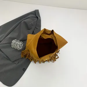 Brown tassel tote bag with suede texture shown from a top-down view on a grey blazer