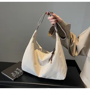 Detail van beige canvas hobo tas met contrastband en kwastje op een model