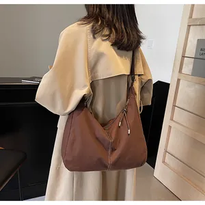 Close-up van bruine canvas hobo tas met witte contraststiksels en minimalistisch design