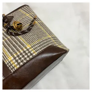 Detailansicht des Vintage-Karomusters und der braunen Ledernaht der Beuteltasche