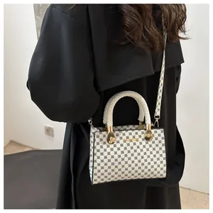 Dettaglio borsa a mano con stampa intrecciata, hardware dorato e tracolla chic