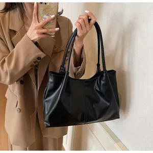 Close-up of a black pleated faux leather tote bag showing soft matte texture and spacious design