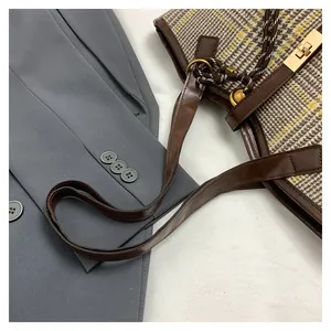 Detail der Vintage-Karo-Einkaufstasche mit braunem Lederbesatz und goldenem Verschluss