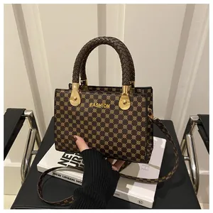 Dettaglio borsa retrò marrone con motivi geometrici dorati e manici intrecciati