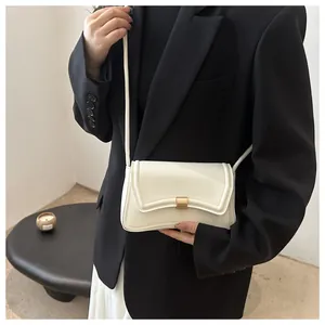 Detail of off-white leather shoulder bag with unique curved flap and gold metal lock