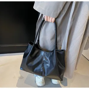 Detail of black pleated tote bag with matte PU leather texture and long shoulder straps
