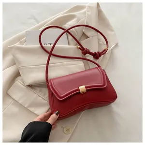 Close-up of deep red PU leather shoulder bag with gold buckle and stylish knot strap