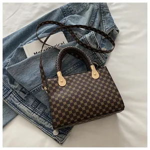 Dettaglio del manico intrecciato e stampa geometrica su borsa a tracolla marrone su denim