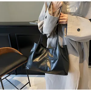 Detail of black matte leather tote bag with vertical stitching and soft draping effect
