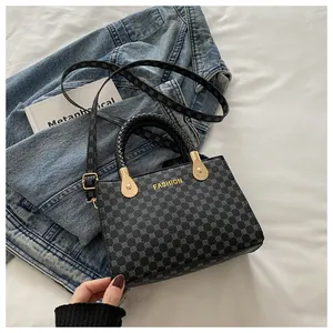 Dettaglio della borsa a tracolla con stampa geometrica e manico intrecciato su denim