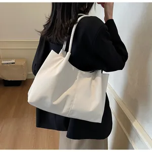 Detail of white pleated tote bag with vertical stitching shown on model shoulder