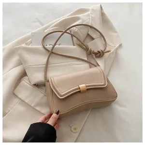 Detail of beige leather bag featuring a curved flap and gold rectangular buckle closure
