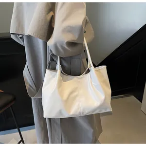Close-up of white oversized pleated tote bag showing the textured PU leather and stitching