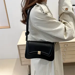 Chic black minimalist leather shoulder bag with curved bottom and gold metal buckle