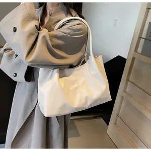 Close-up of a white pleated tote bag showing the soft faux leather texture and handle