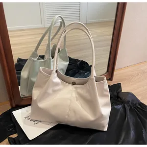 Detail of cream pleated tote bag featuring magnetic buckle closure and slim shoulder straps