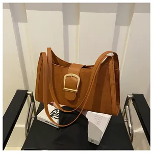 Close-up of caramel suede underarm bag with a bold gold square buckle and leather trim