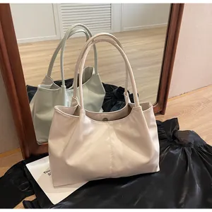 Detail of beige tote bag showing smooth faux leather texture and metal magnetic closure