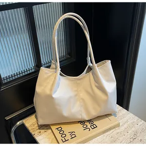 Close-up of a cream pleated tote bag with double straps on a marble surface