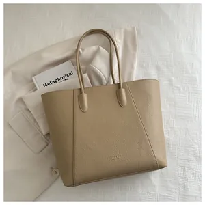 Detail of apricot faux leather tote bag showing fine lychee grain texture and minimalist design
