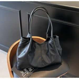 Detail of minimalist black pleated PU leather tote bag with stylish shoulder straps
