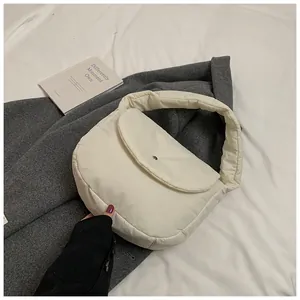 Close-up of a white quilted puffer shoulder bag with a magnetic metal buckle closure
