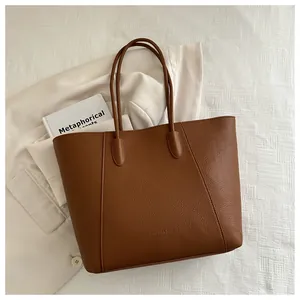 Close-up of brown litchi pattern leather tote bag with slim straps and debossed detail