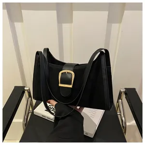 Detail of black suede shoulder bag featuring a gold square buckle on a magazine