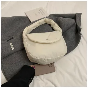 Close-up of white puffer shoulder bag showing soft padded fabric and magnetic snap buckle
