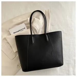 Detail view of black lychee-textured leather tote bag with elegant metallic logo lettering
