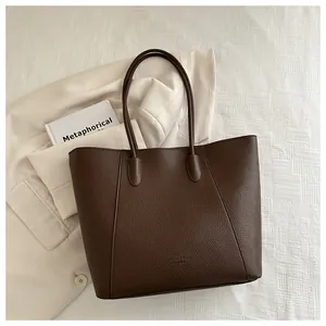 Close-up of dark brown leather tote bag with lychee texture and stitching detail