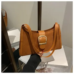 Detailed close-up of brown suede crescent bag with smooth leather trim and gold buckle