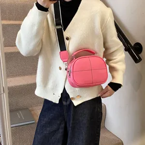 Pink crossbody square bag with wide striped strap and cross stitching detail on leather