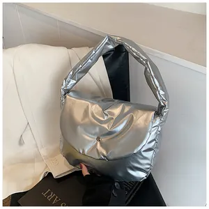 Close-up of metallic silver puffer shoulder bag with a minimalist round snap button and flap