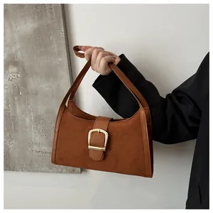 Close-up of vintage brown suede shoulder bag with a prominent gold square metal buckle