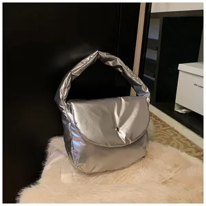 Detail of silver metallic puffer tote bag with magnetic snap button on white rug