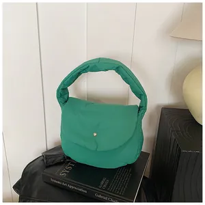 Detail of green puffy shoulder bag with golden round metal buckle on art books