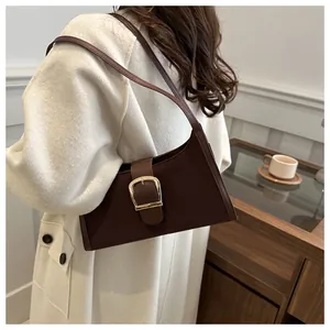 Detail of a dark brown vintage hobo bag with a large gold buckle shown on a model's shoulder