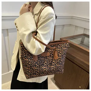 Detail shot of leopard print tote bag with brown leather handles worn by a model
