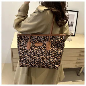Detailed view of leopard print tote bag with brown leather trim on beige trench coat