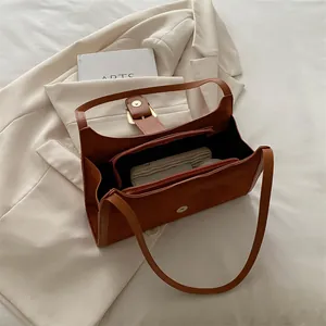 Brown leather underarm bag with gold magnetic buckle and internal zip compartments