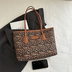 Chic leopard print tote bag with brown leather straps styled on a black blazer