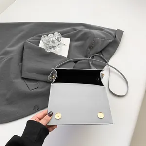 Sac bandoulière carré minimaliste en cuir gris clair avec détails dorés et fermoir aimanté